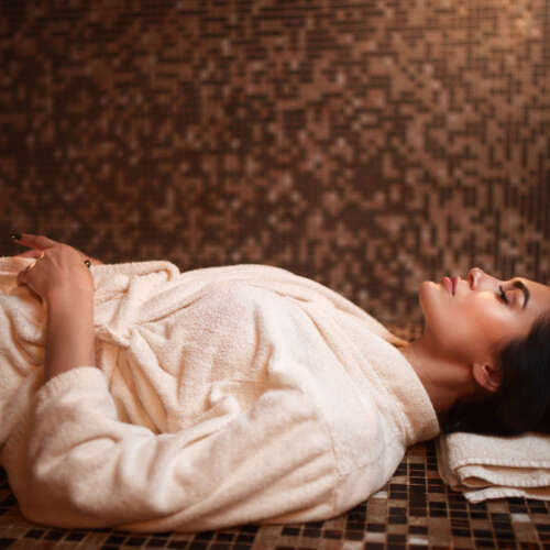 Woman lying on a hot stone, turkish hamam, sauna, side view. Healthcare, skincare and body care